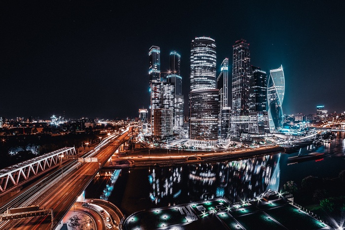 Moscow City skyscrapers at night with river and bridge
