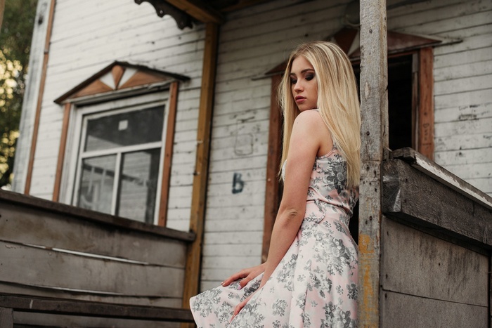 Blonde woman in a floral dress near an old house