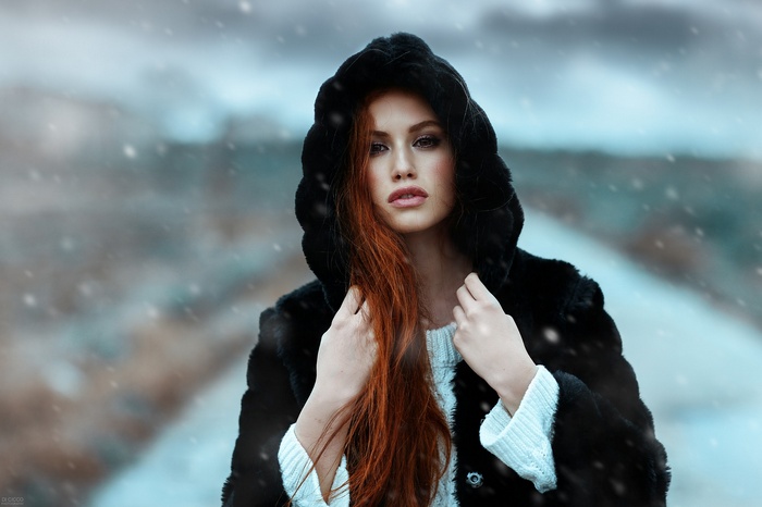 Woman with red hair in a fur hood in the snow