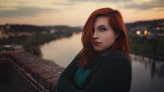 Redhead woman with arms crossed outdoors at sunset