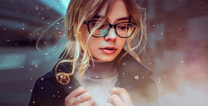Woman with blonde hair wearing glasses and a coat