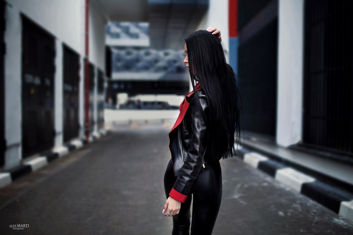 Woman with long black hair in a leather jacket outdoors