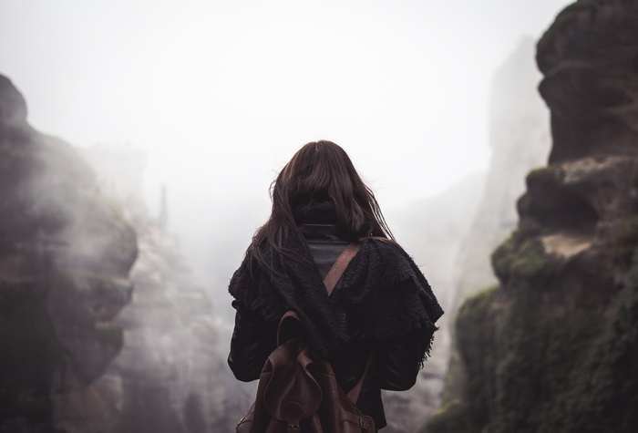 Woman with backpack in foggy mountains