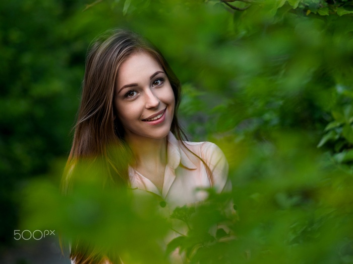 Young woman smiling through green foliage