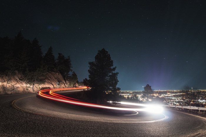 Light painting on a winding road at night with city lights