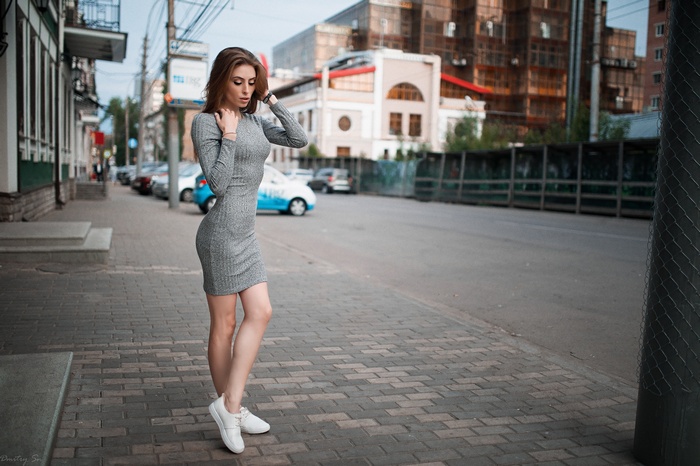 Woman in grey dress standing on sidewalk