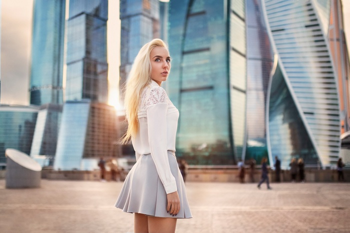 Woman in skirt and blouse in front of skyscrapers