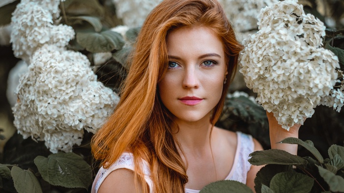 Redhead woman with blue eyes among white flowers