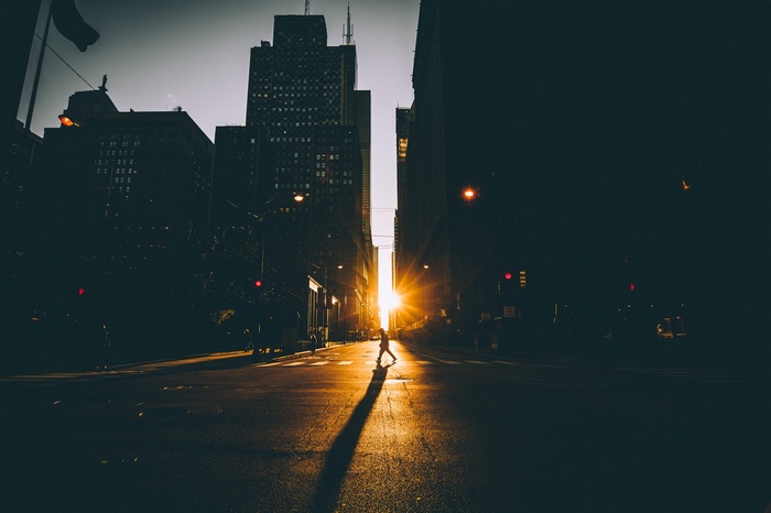 Person crossing street at sunset with skyscrapers