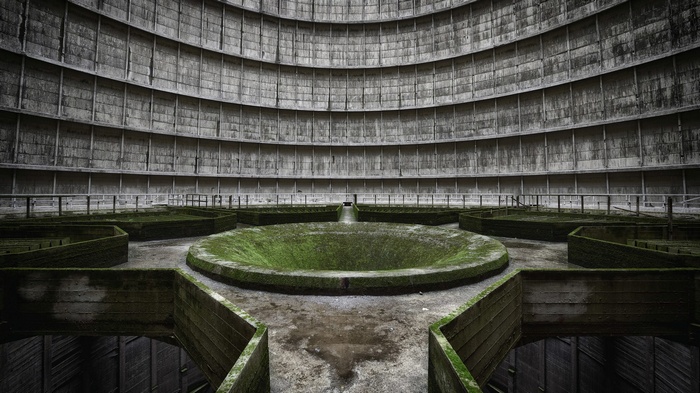Interior of a large, abandoned concrete cooling tower with moss