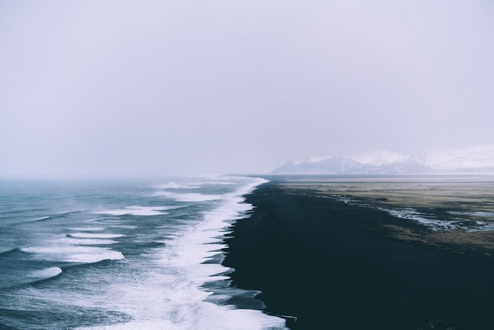 Black sand beach with waves and mountains