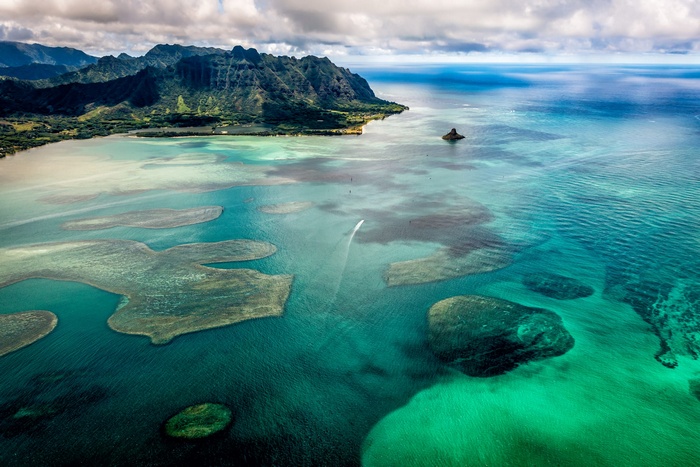 Aerial view of Oahu coastline with mountains and coral reefs