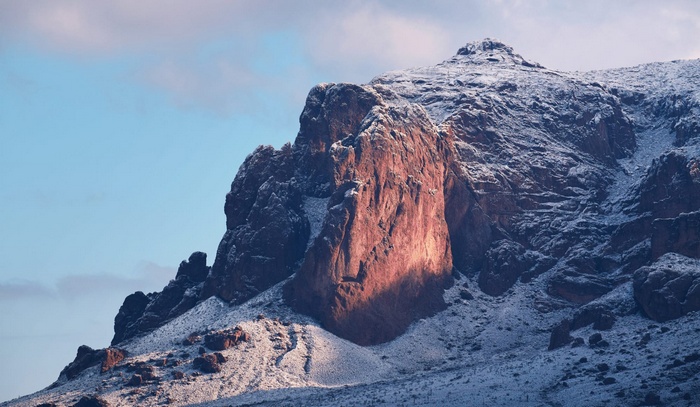 Snow-covered rocky mountain peak at sunrise