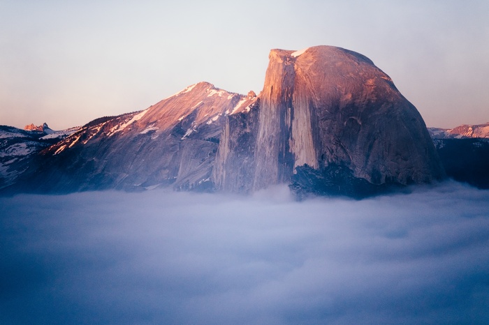 Half Dome mountain peak above clouds at sunrise