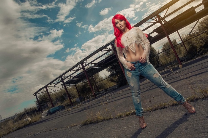 Woman with red dyed hair in torn jeans and white top