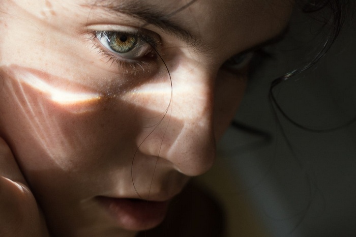 Close-up portrait of a woman with green eyes and sun rays