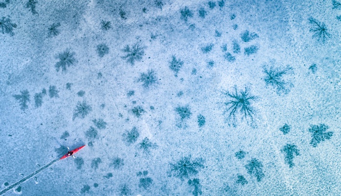 Red kayak on a frozen lake with ice patterns