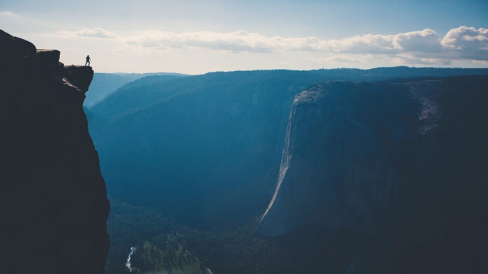 Man standing on cliff edge overlooking mountains