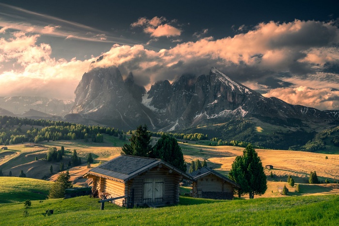 Wooden cabins in the Italian Alps with dramatic clouds