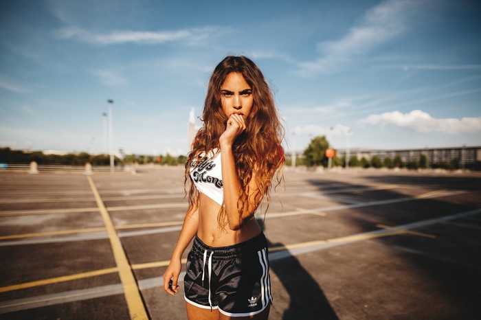 Woman in Adidas shorts and crop top in parking lot