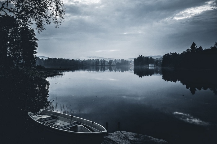 Boat on a calm lake with trees and clouds
