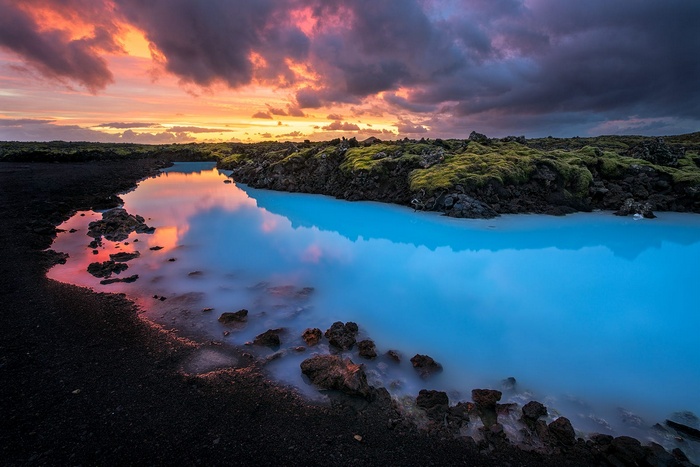 Blue lagoon with lava rocks and sunset sky