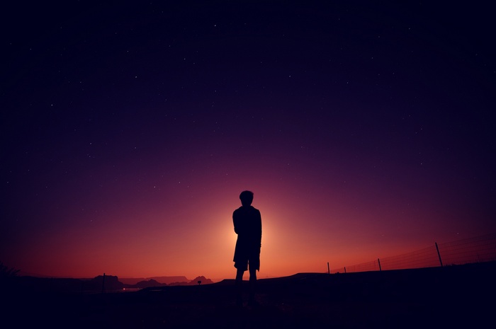 Silhouette of a person against a starry dusk sky