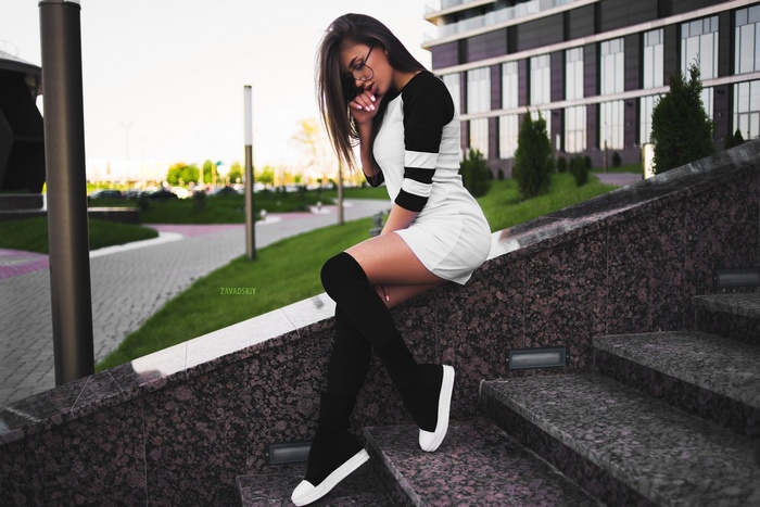 Woman in dress and stockings sitting on stairs