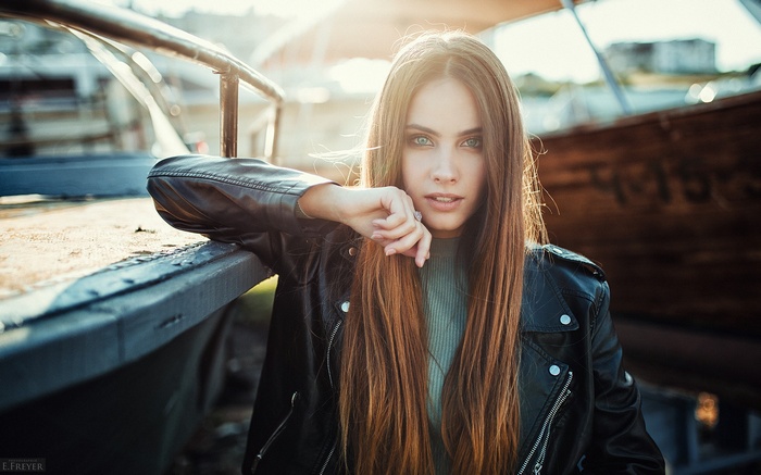 Woman with long hair and blue eyes wearing a leather jacket