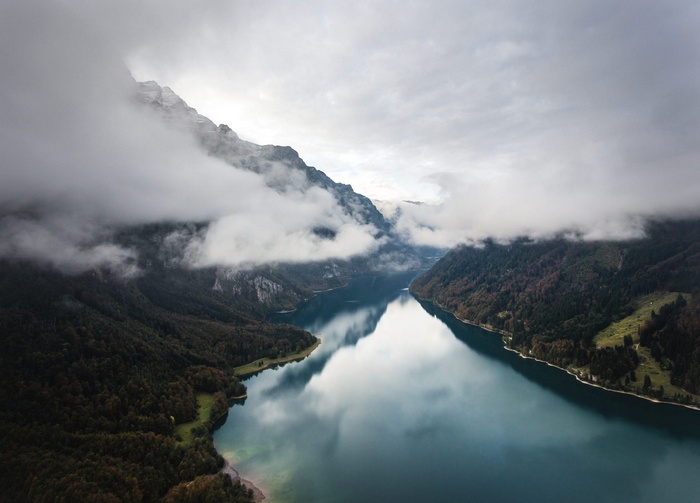 Misty mountains over a calm lake with forest reflections