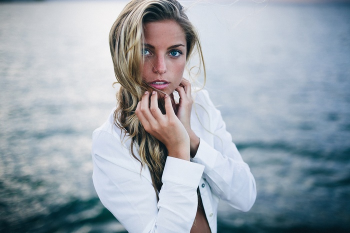 Woman with blonde hair and blue eyes wearing a white shirt