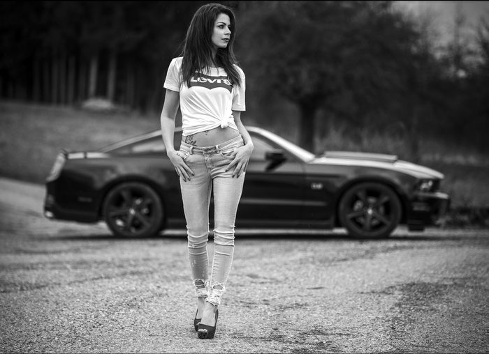Woman in Levi's jeans and shirt with tattoo and car