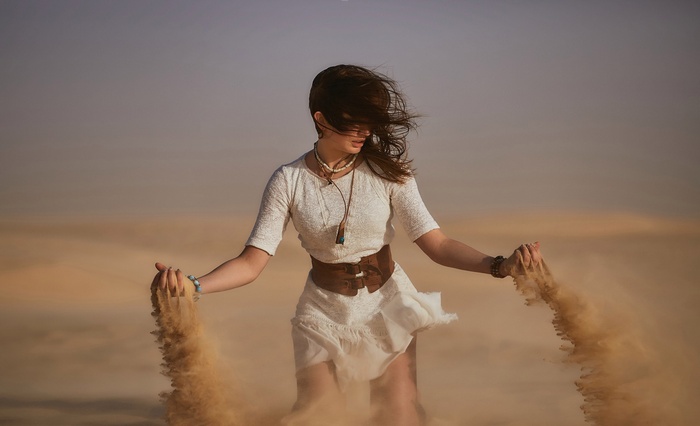 Woman in white dress in desert with sand