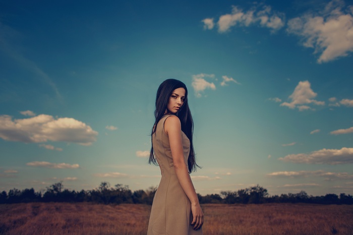 Woman in a dress in a field under the sky