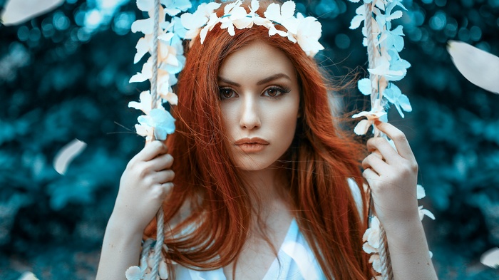 Woman with red hair wearing a flower crown on a swing