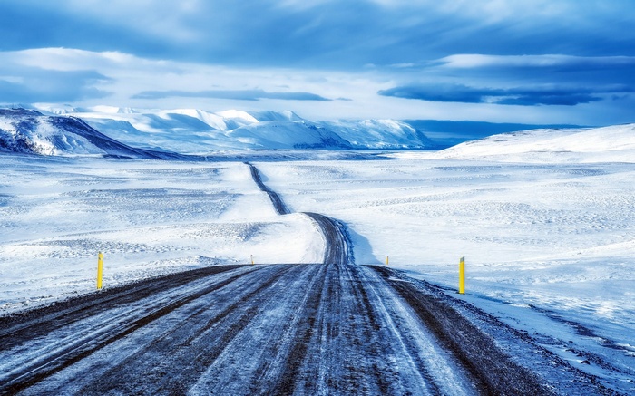 Snowy road through a winter landscape with mountains