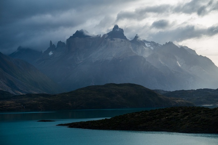 Jagged mountains shrouded in mist over a turquoise lake
