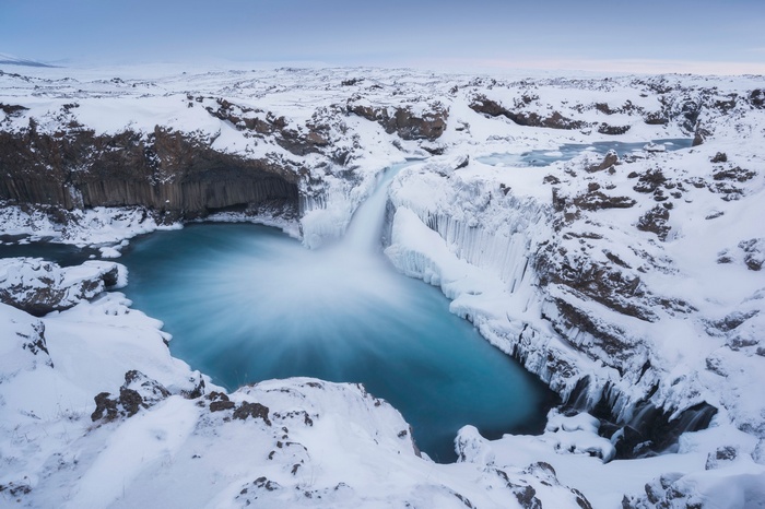 Frozen waterfall in Iceland with blue water
