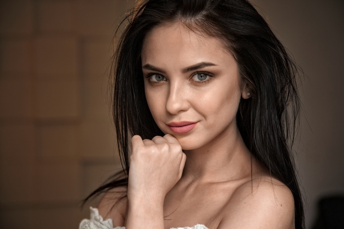 Woman with dark hair resting chin on hand