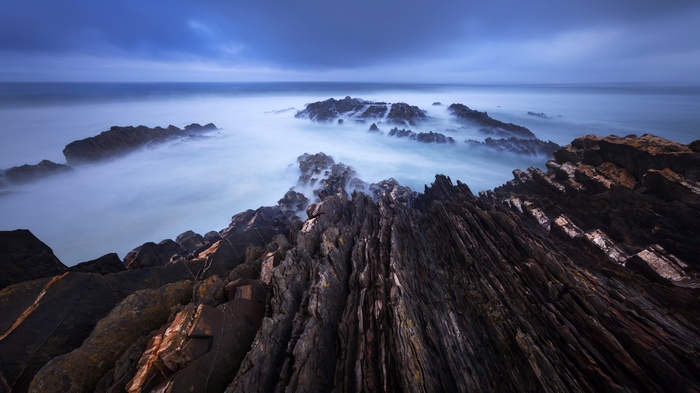Jagged rocks in misty ocean at dusk