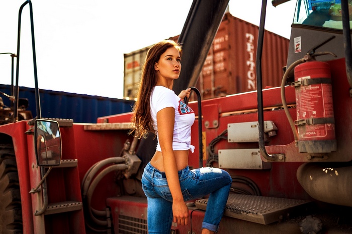 Woman in jeans and t-shirt posing on a vehicle