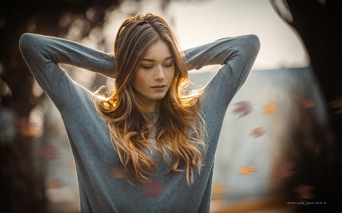 Woman with arms up in fall with leaves