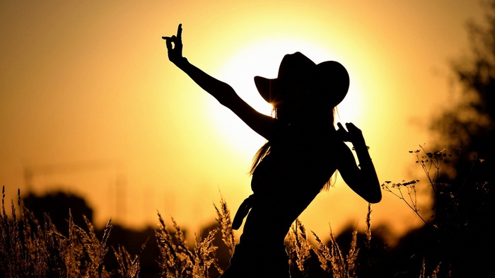 Silhouette of a woman in a cowboy hat at sunset
