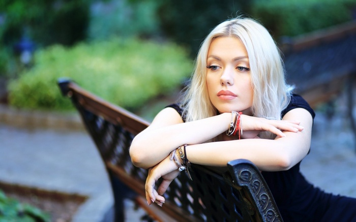 Woman with blonde hair sitting on a park bench