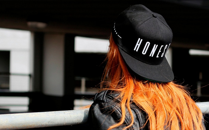 Woman with orange hair wearing a black baseball cap