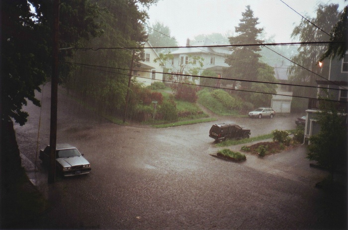 Street during heavy rain with cars and houses