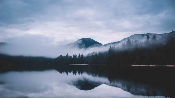 Misty mountains reflected in a calm lake