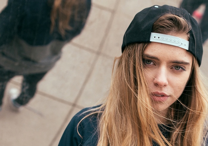 Woman wearing a black baseball cap looking at the camera
