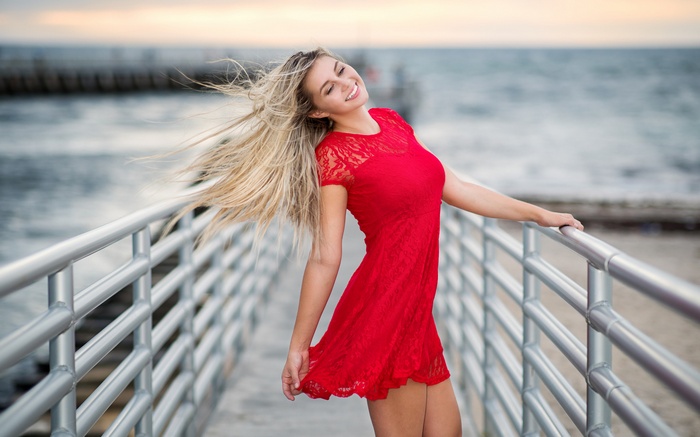 Woman in red dress on pier with wind blowing hair