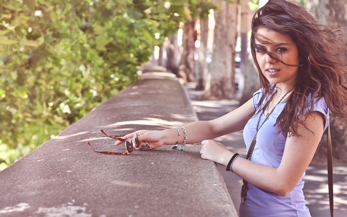Woman with sunglasses and blue shirt on a wall